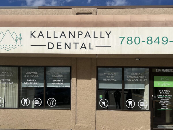 A dental clinic storefront for Kallanpally Dental featuring large windows, the clinic's name and phone number prominently displayed above, and various service icons on the windows. The setting is bright and welcoming.