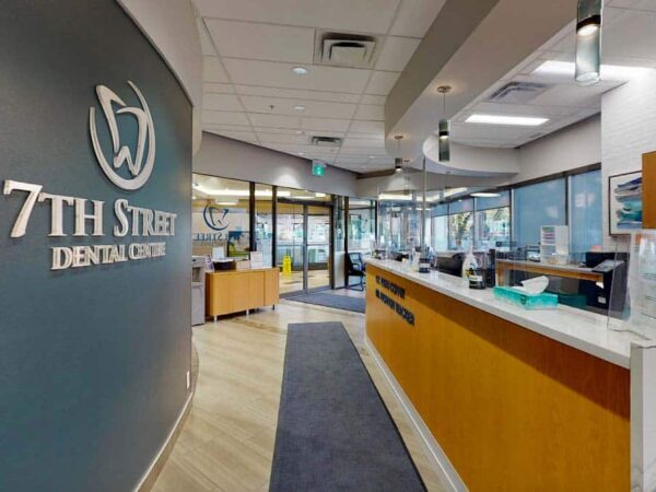 Interior of 7th Street Dental Center featuring a reception area with a curved desk, modern decor, and large windows allowing natural light. The space is welcoming and designed for patient comfort.