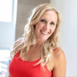 A smiling woman with long, wavy blonde hair wears a red tank top. She poses in a bright, softly-lit space, conveying warmth and approachability.