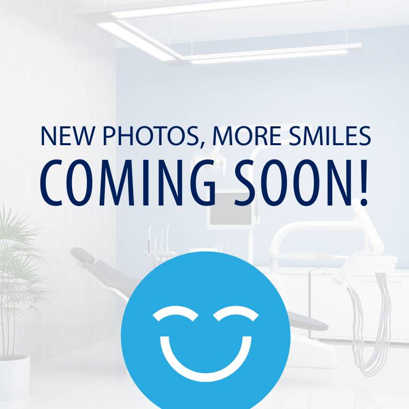 A bright dental office waiting area with modern equipment is featured, alongside a cheerful blue smiley face icon. The text "NEW PHOTOS, MORE SMILES COMING SOON!" suggests an upcoming update or announcement related to the practice.