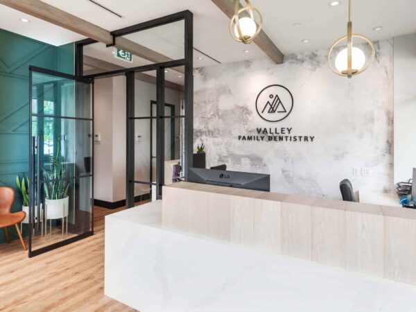 A modern reception area featuring a sleek front desk, a company logo on the wall, and stylish seating. Large windows provide natural light, and glass partitions create an open, airy feel.