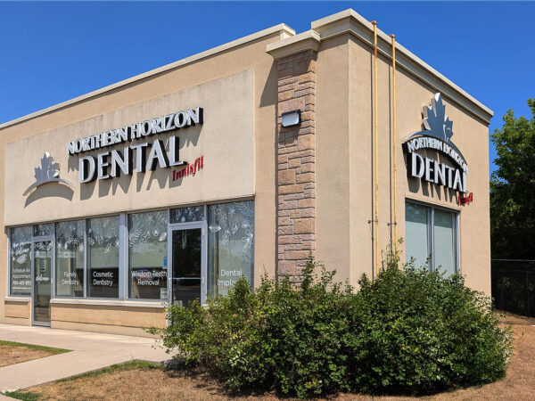 A dental clinic building with large windows and a sign that reads "Southern Horizon Dental." The design features light-colored stone and brick accents, complemented by surrounding greenery and a clear blue sky.