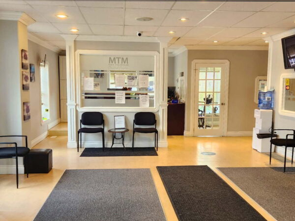 A welcoming reception area featuring a reception desk, comfortable seating, and various informational displays. The space is well-lit with a clean, modern aesthetic, designed for visitors in a professional setting.