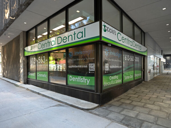 A bright dental office exterior featuring large windows and a green and white sign that reads "Central Dental." The entrance is easily accessible from the sidewalk, offering a welcoming atmosphere for patients.
