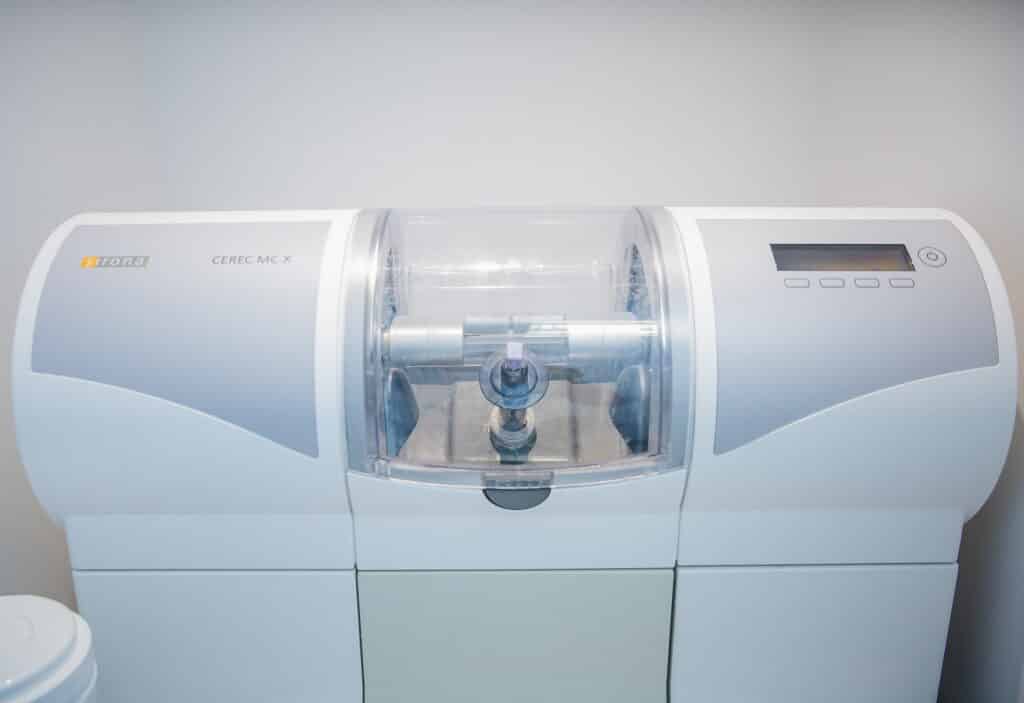 A modern dental equipment unit with a clear viewing area, designed for precision. The machine features a digital display and a sleek, white design, indicating its advanced technology for dental procedures.