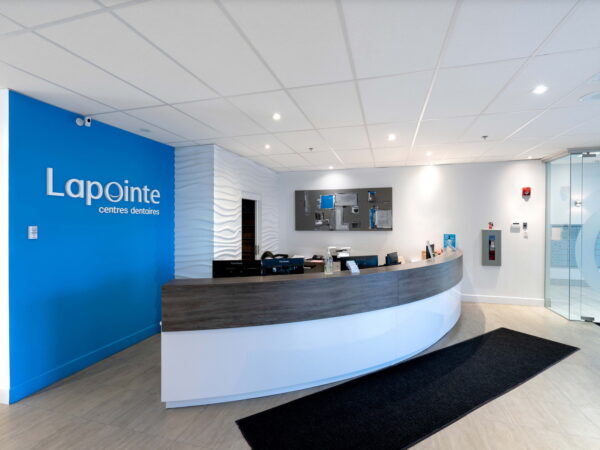 Reception area of a modern office featuring a curved wooden desk, blue accent wall with the logo "Lapointe," and sleek decor.