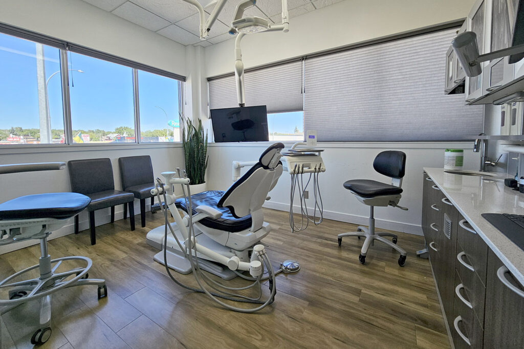 A bright dental office featuring a treatment chair, a patient chair, and modern equipment. Large windows allow natural light to illuminate the space, creating a welcoming atmosphere for patients. The 123Dentist Smiley adds a cheerful touch to the environment.