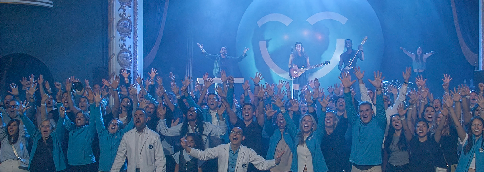 A lively crowd joyfully celebrates the launch of the "Smiles Across Canada" campaign, raising their hands in excitement. In the background, a performer plays guitar on stage, accompanied by colorful lighting and a large 123Dentist Smiley adding a playful touch to the atmosphere.